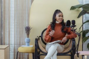 Frau mit Notizbuch und Mikrofon beim Aufnehmen eines Podcasts